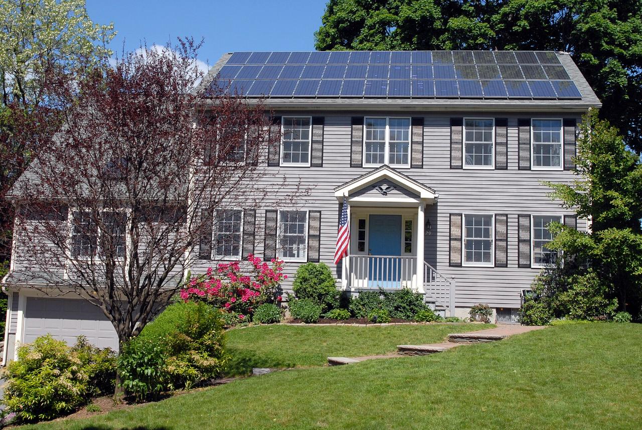 A two-story home with a rooftop solar array and blossoming trees in spring
