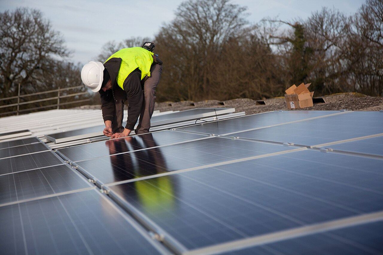 Two installers fitting solar panels on a roof