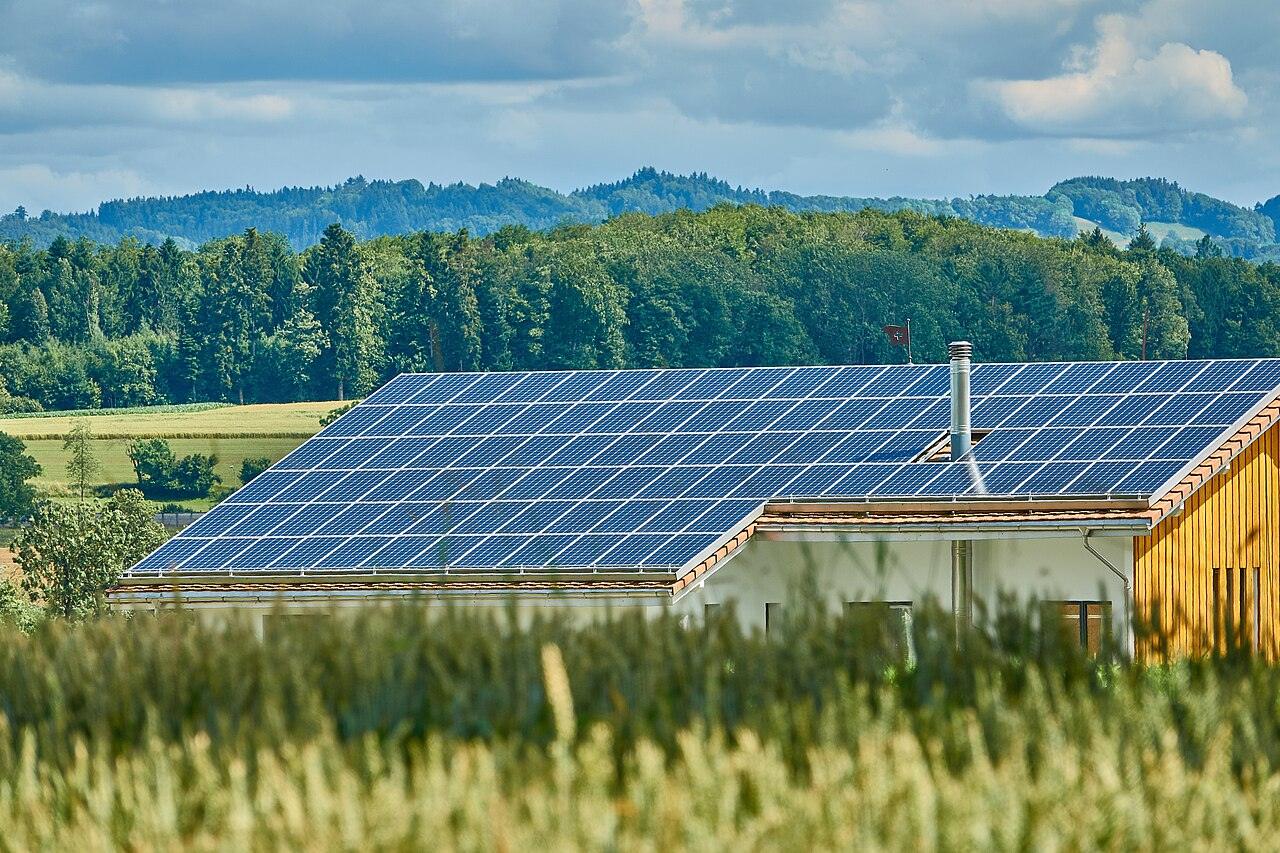Solar panels on the roofs of farm buildings in a green field